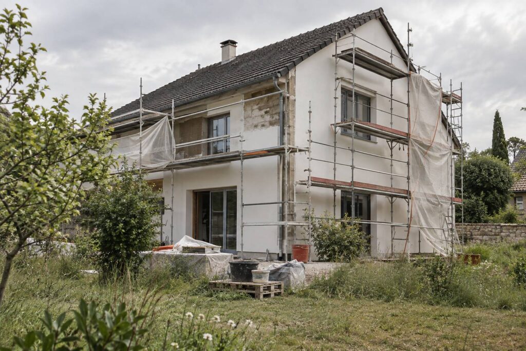 Maison en rénovation avec échafaudage et bâches de protection sur la façade