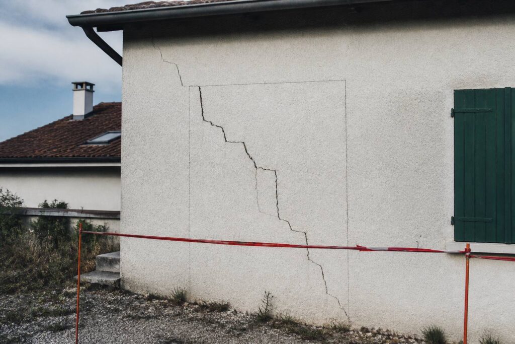 Fissure en escalier sur un mur de façade délimitée au crayon et protégée par une rubalise