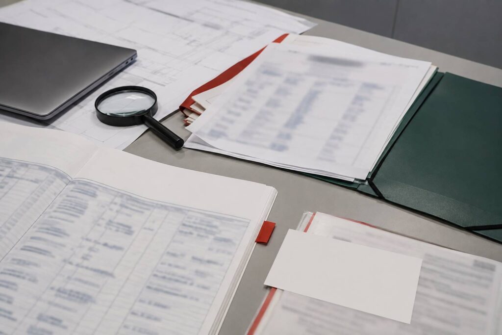 Documents d'entreprise floutés avec loupe et ordinateur fermé sur un bureau